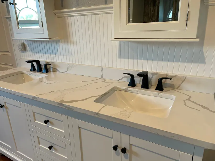 White veined stone vanity top with two undermount sinks and matte black faucets