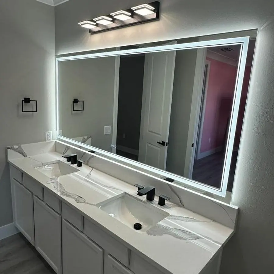 White veined stone double vanity under a large LED mirror