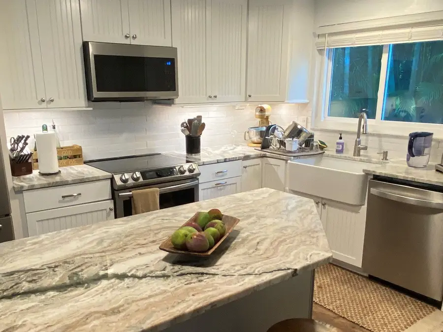 Kitchen island in Fantasy Brown dolomite with a white tile backsplash and a farmhouse sink