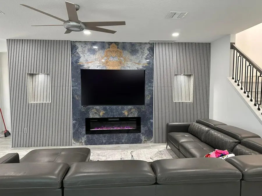 Electric fireplace and TV wall clad in blue and gold exotic stone between slatted wood panels
