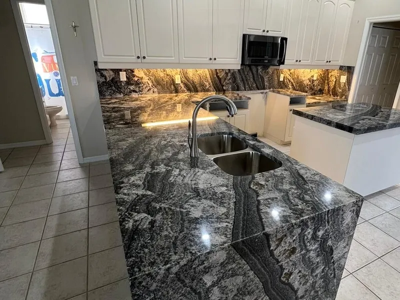 Kitchen island in dark Blue Dream granite with a waterfall side and a matching full height backsplash