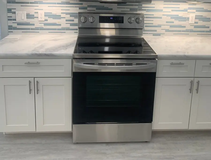 Shadow Storm marble countertops with a blue and white glass mosaic backsplash behind the range