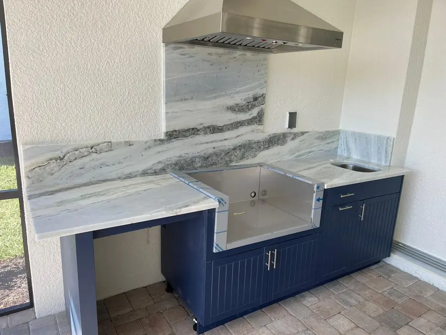 Outdoor kitchen with Blue Lumen marble countertops and backsplash over navy cabinets