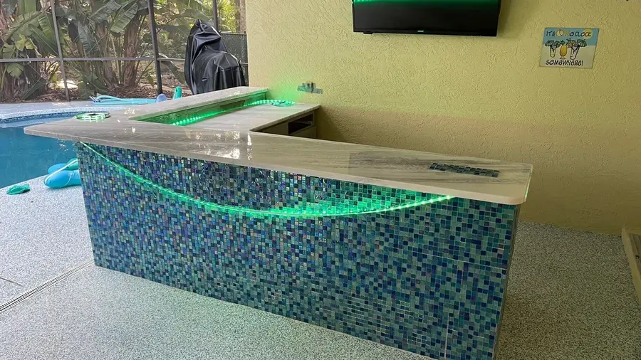 Poolside bar with a light stone top and a blue glass mosaic tile front