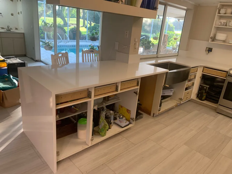 Absolute White quartz countertops just installed over open kitchen cabinets, with a farmhouse sink and a waterfall end panel
