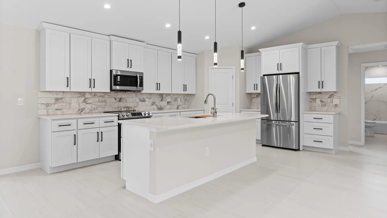 White shaker kitchen with an Absolute White quartz island and perimeter countertops, black pendant lights, a marble look tile backsplash and a stainless refrigerator