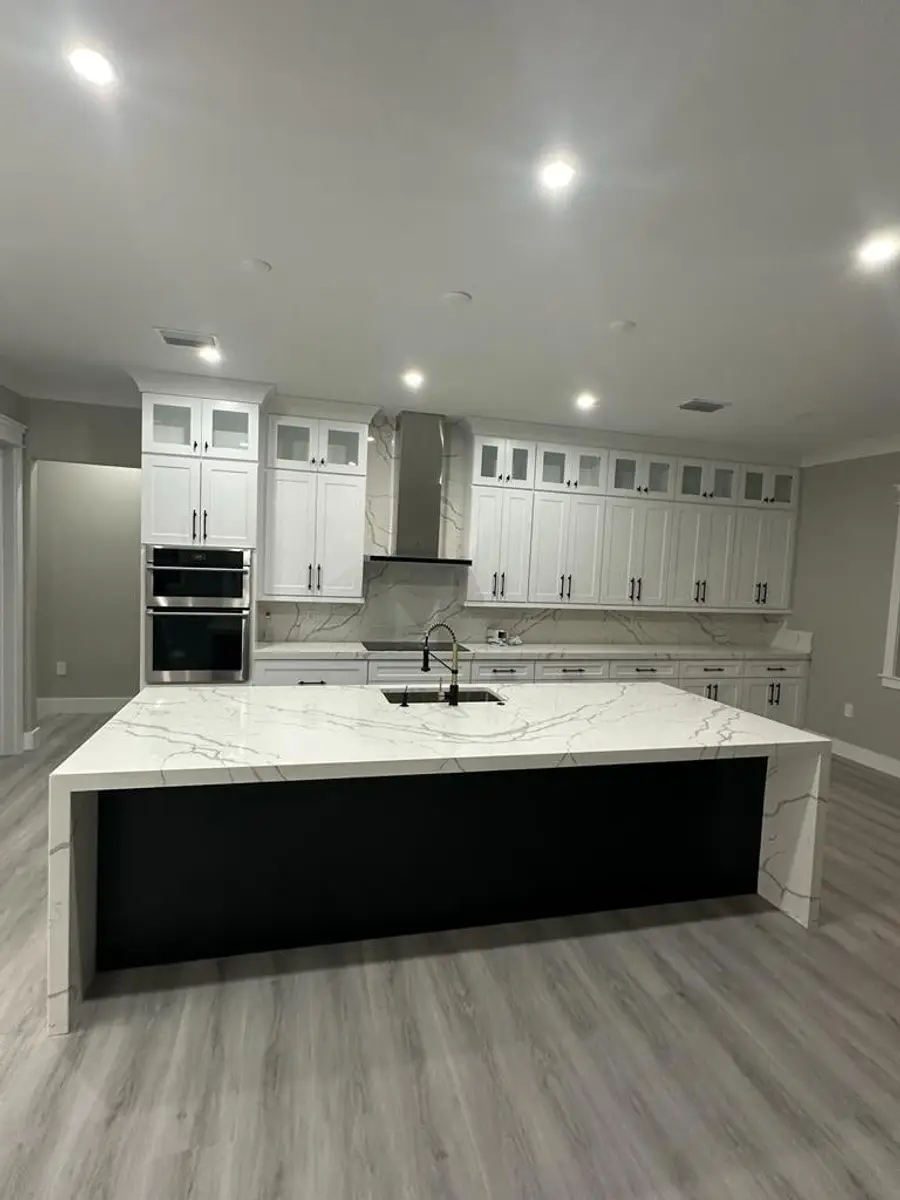 White kitchen with a black island wrapped in Calacatta quartz with waterfall and mitered edges