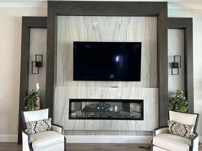 Linear fireplace and TV wall clad in White Pearl quartzite inside a dark wood frame